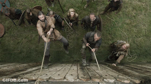 A Group Of Men Are Pulling Ropes Over A Wooden Bridge GIF