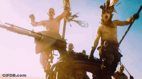 A Group Of Men Are Riding On The Back Of A Vehicle In A Desert . GIF