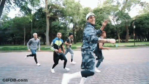 A Group Of Men Are Running On A Brick Road In A Park GIF