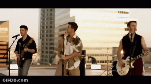 A Group Of Men Are Singing And Playing Guitars In Front Of A Sign That Says Bre GIF