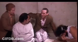 A Group Of Men Are Sitting Around A Woman In A Strait Jacket . GIF