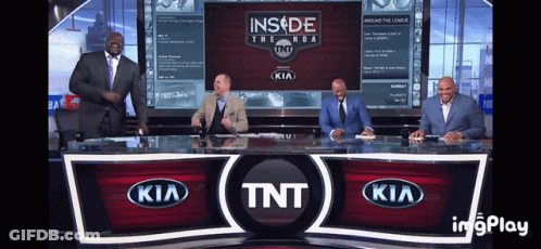 A Group Of Men Are Sitting At A Desk In Front Of A Tnt Kia Sign GIF