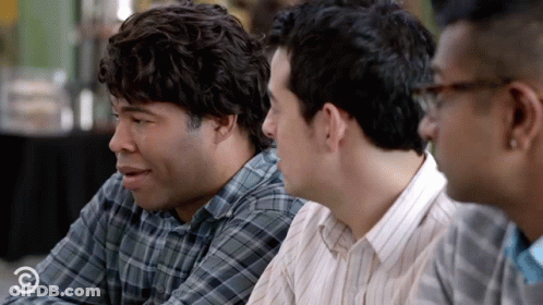 A Group Of Men Are Sitting At A Table And One Of Them Is Wearing A Plaid Shirt That Says Comedy Central On It GIF