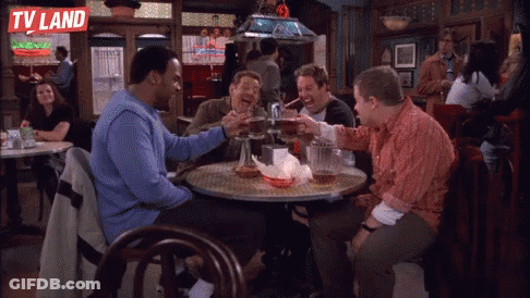 A Group Of Men Are Sitting At A Table In A Bar With A Tv Land Logo On The Wall GIF