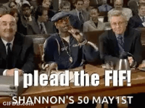 A Group Of Men Are Sitting At A Table In A Courtroom And A Man Is Holding A Microphone . GIF