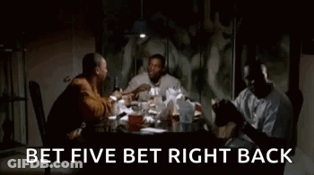A Group Of Men Are Sitting At A Table In A Dark Room Talking . GIF