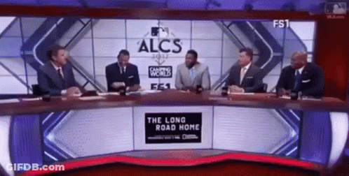 A Group Of Men Are Sitting At A Table In Front Of A Large Screen That Says Alcs GIF