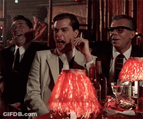 A Group Of Men Are Sitting At A Table With A Red Lamp GIF