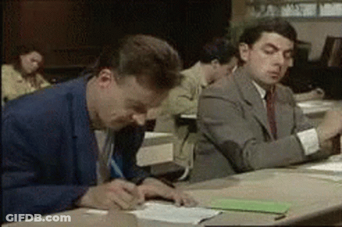 A Group Of Men Are Sitting At A Table Writing On Papers . GIF