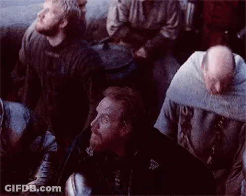 A Group Of Men Are Sitting In A Dark Room Looking Up At Something . GIF