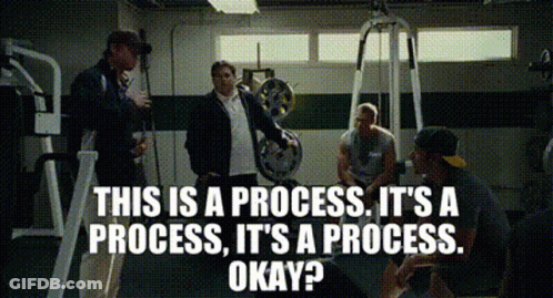 A Group Of Men Are Sitting In A Gym Talking About A Process GIF