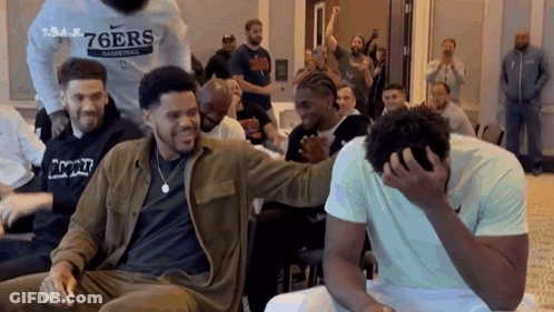 A Group Of Men Are Sitting In A Room Laughing And One Man Is Covering His Face . GIF