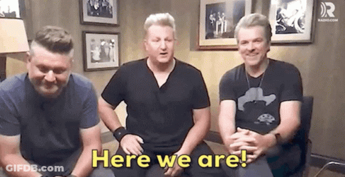 A Group Of Men Are Sitting In A Room With The Words Here We Are . GIF