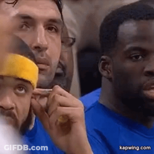 A Group Of Men Are Sitting In A Stadium Watching A Game . One Of The Men Is Wearing A Yellow Headband . GIF