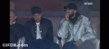 A Group Of Men Are Sitting In A Stadium Watching A Game . GIF