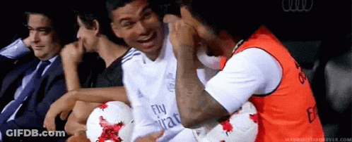 A Group Of Men Are Sitting In A Stadium With Soccer Balls And One Of Them Is Wearing A Fly Emirates Shirt . GIF