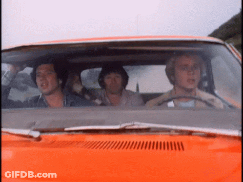 A Group Of Men Are Sitting In An Orange Car Looking Out The Window GIF