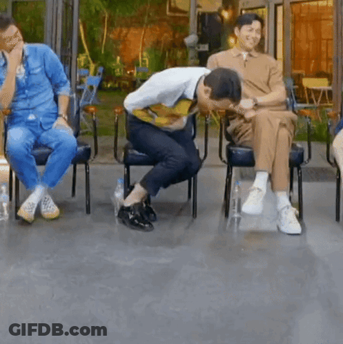 A Group Of Men Are Sitting In Chairs And One Of Them Is Kneeling Down . GIF