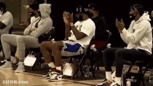 A Group Of Men Are Sitting In Folding Chairs On A Basketball Court . GIF