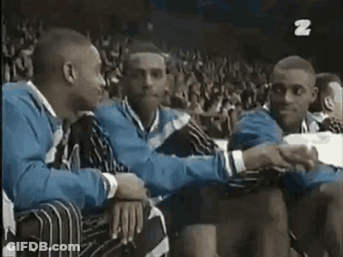A Group Of Men Are Sitting Next To Each Other In A Stadium And Shaking Hands . GIF