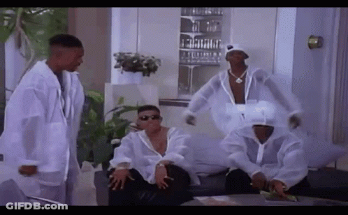 A Group Of Men Are Sitting On A Couch In A Living Room Wearing White Jackets . GIF