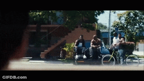 A Group Of Men Are Sitting On The Side Of A Street GIF