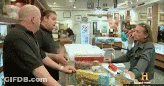 A Group Of Men Are Standing Around A Counter In A Store That Says History On The Bottom GIF
