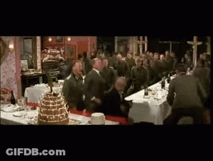 A Group Of Men Are Standing Around A Long Table With A Cake On It GIF