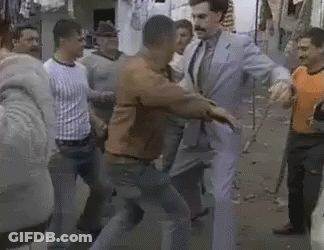 A Group Of Men Are Standing Around A Man In A Suit And Tie Standing In A Crowd . GIF