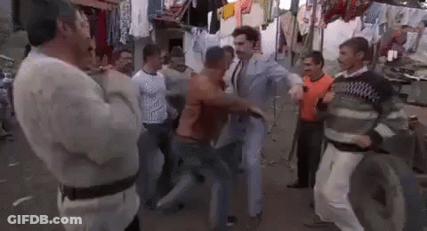 A Group Of Men Are Standing Around A Man In A Suit Dancing On A Street . GIF