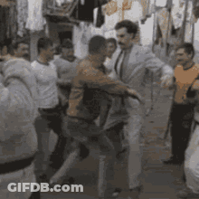 A Group Of Men Are Standing Around A Man In A Suit . GIF