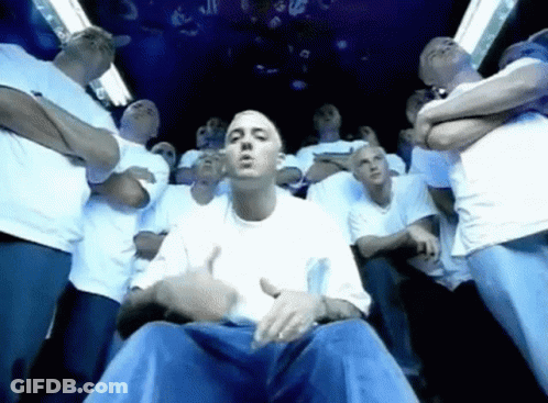 A Group Of Men Are Standing Around A Man In A White Shirt And Blue Jeans . GIF