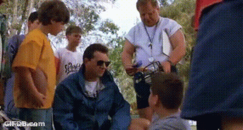 A Group Of Men Are Standing Around A Man Sitting On The Ground . GIF