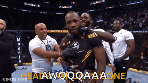 A Group Of Men Are Standing Around A Man With The Words " Heatawqqqaaaone " Written On The Bottom GIF