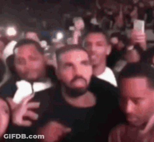 A Group Of Men Are Standing In A Crowd Holding Their Cell Phones . GIF