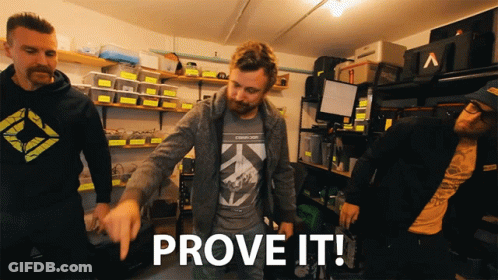A Group Of Men Are Standing In A Garage And One Of Them Is Pointing To The Word Prove It GIF