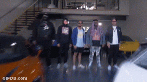 A Group Of Men Are Standing In A Garage With A Car In The Background GIF