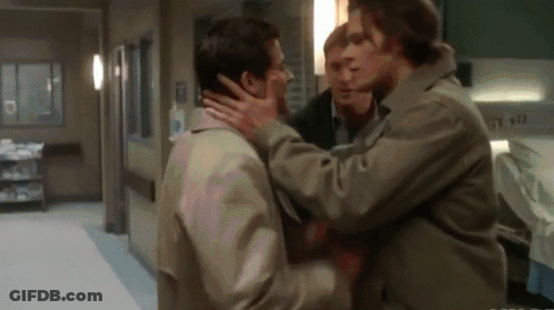 A Group Of Men Are Standing In A Hallway And One Of Them Is Holding Another Man 'S Face GIF