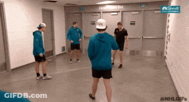 A Group Of Men Are Standing In A Hallway With A Sign That Says Nhl GIF