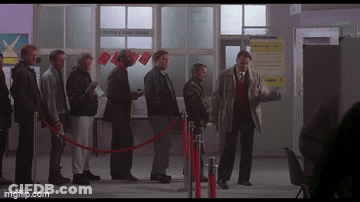 A Group Of Men Are Standing In A Line Behind A Red Rope And A Sign That Says " Moving & Storage " GIF
