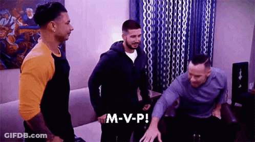 A Group Of Men Are Standing In A Living Room And One Of Them Is Saying M-V-P ! GIF