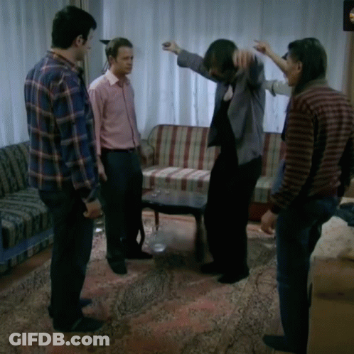 A Group Of Men Are Standing In A Living Room With A Couch And A Table GIF