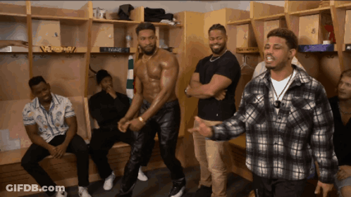A Group Of Men Are Standing In A Locker Room And One Of Them Is Wearing A Shirtless Shirt GIF