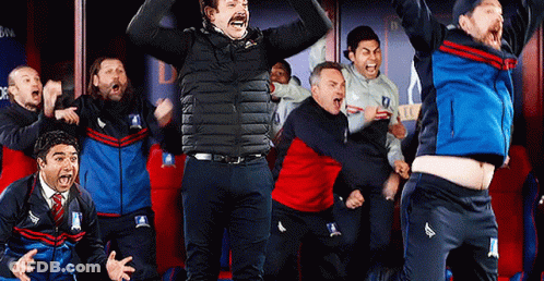 A Group Of Men Are Standing In A Locker Room Celebrating A Win . GIF