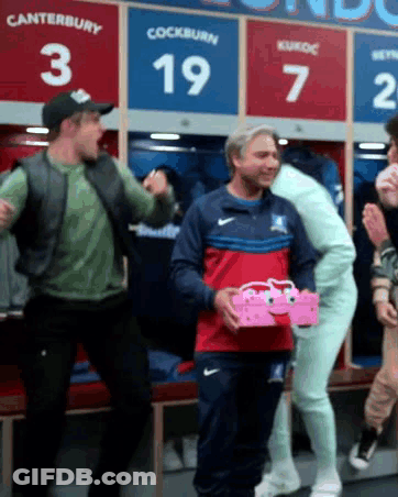 A Group Of Men Are Standing In A Locker Room With The Number 19 On The Wall GIF