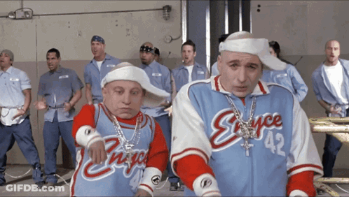 A Group Of Men Are Standing In A Room And One Of Them Has The Number 42 On His Jersey GIF