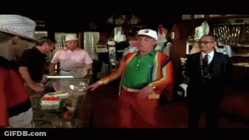 A Group Of Men Are Standing In A Room And One Of Them Is Wearing A Green Sweater GIF