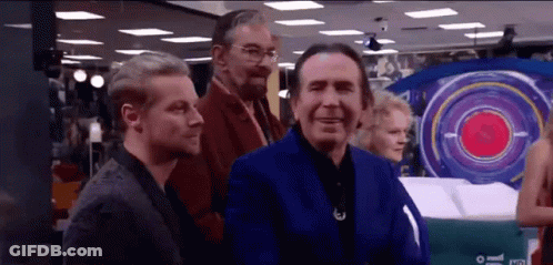 A Group Of Men Are Standing In A Room With A Large Target In The Background . GIF