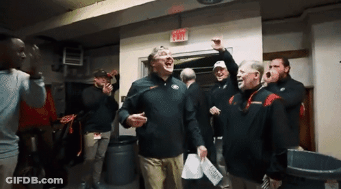 A Group Of Men Are Standing In A Room With An Exit Sign Above Them GIF