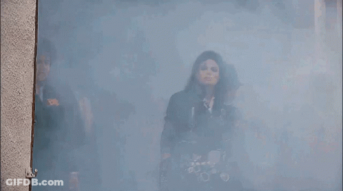A Group Of Men Are Standing In A Room With Smoke Coming Out Of The Door GIF